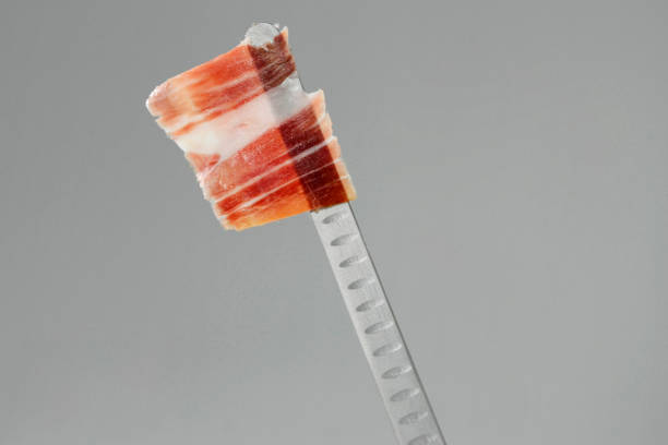 100% iberico pure acorn-fed ham sliced by a knife. Gray background. Pata negra.